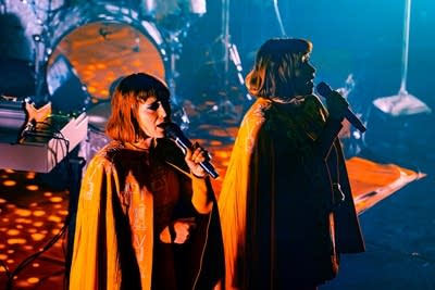 Two musicians sing together onstage