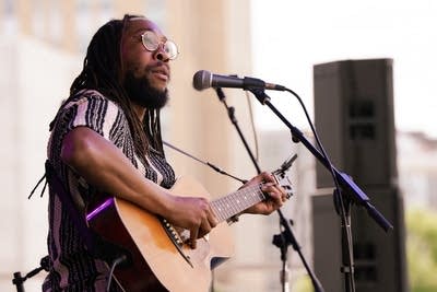 A musician sings and plays guitar onstage