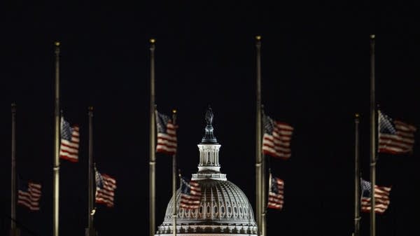 The U.S. Capitol dome is seen beyond American flags