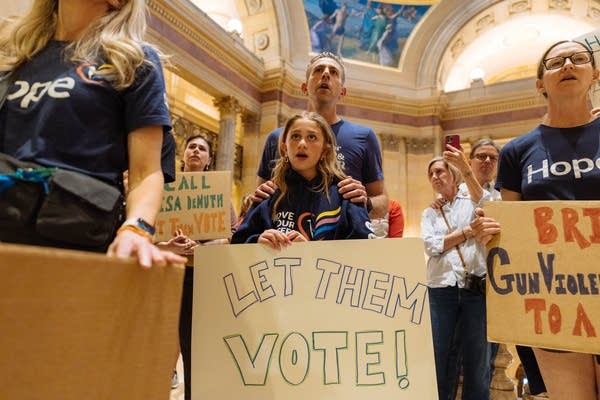 People hold signs at a rally inside the Capitol.