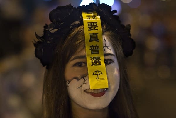 A pro democratic supporter wears a dramatic make-up for Halloween Party in occupied Central district. In her forehead has a sticker with the message.