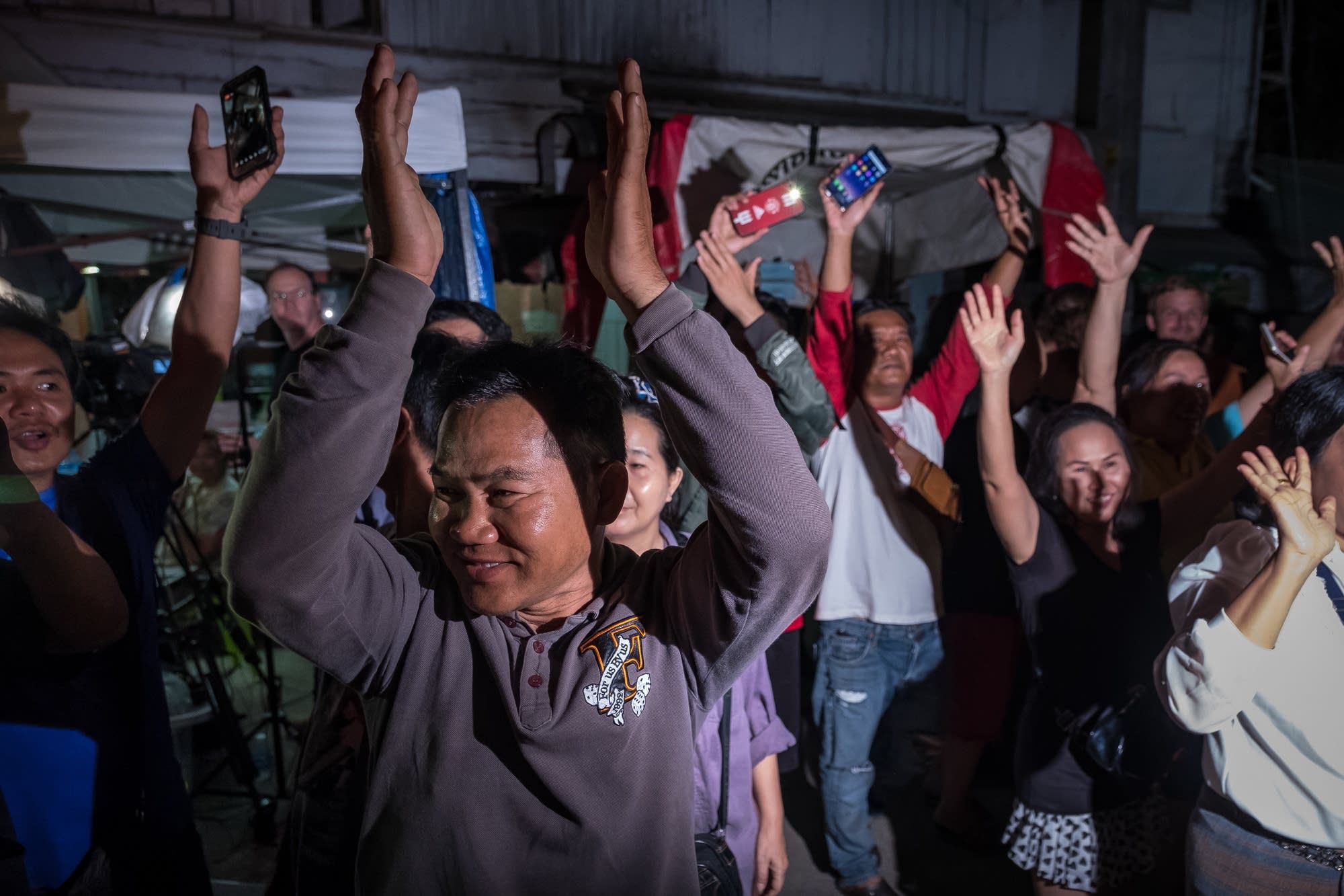 Onlookers cheer as ambulances transport rescued boys to the hospital.
