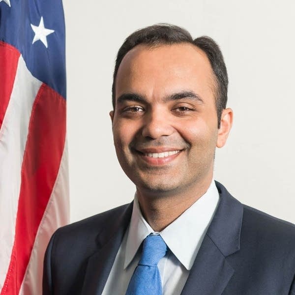CFPB director Rohit Chopra stands next to the American flag and smiles for headshot.