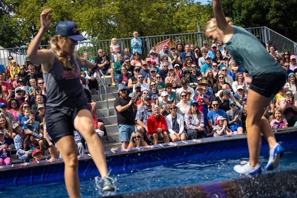 A crowd watches two people log roll