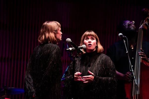 Three musicians performing together onstage in a concert hall