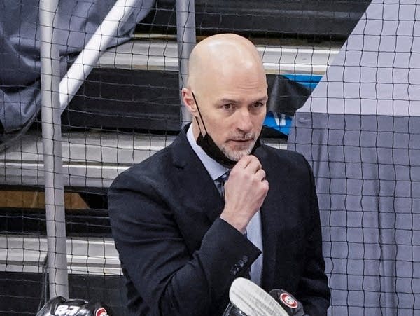 A man in a suit pulls down his face mask.