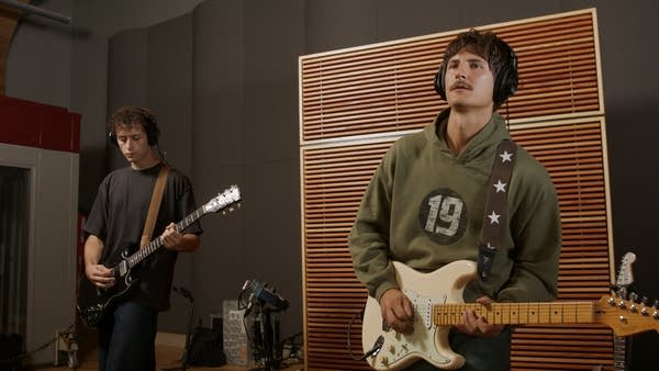 Two guitarists performing in a recording studio