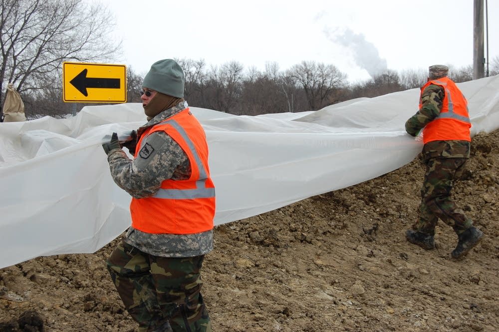 National Guard troops cover the dike in plastic