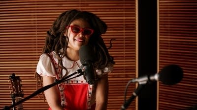 A woman speaks into a microphone in a recording studio