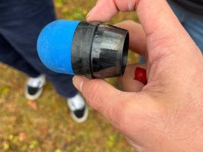 A hand holds a rubber round found near the scene of police action.