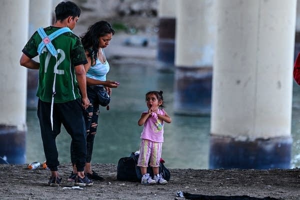 A child looks at a woman and man