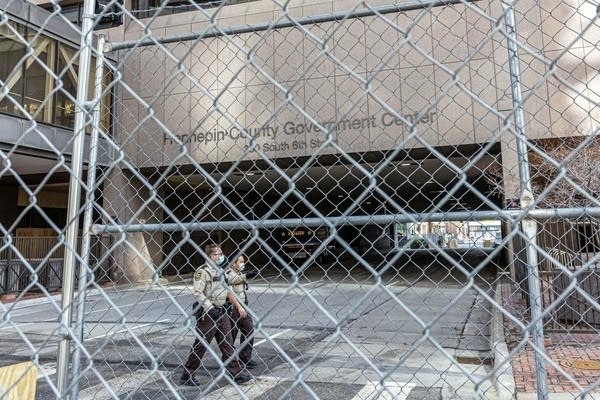 Two law enforcement officers walk behind barricades.