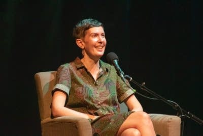 Author Patricia Lockwood and host Kerri Miller converse while sitting in beige armchairs on a large, dark stage.