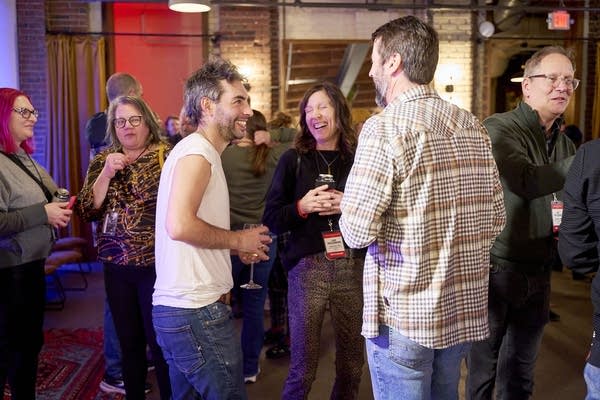 A group of people smile and converse in a small restaurant
