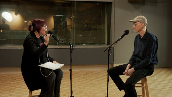 Two people have a conversation in a recording studio