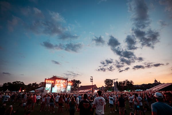 A long view of a band performing onstage at a music festival