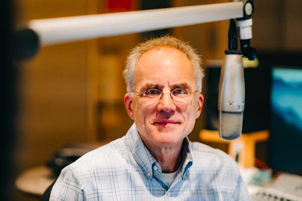 A man poses for a portrait in a broadcast studio