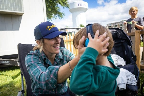 A woman helps a child with his ear muffs