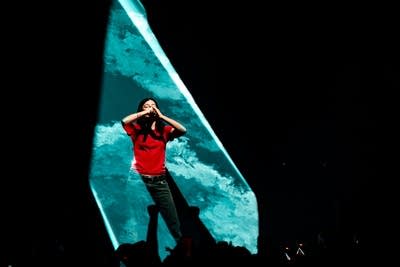 A musician sings and dances onstage in a large music venue
