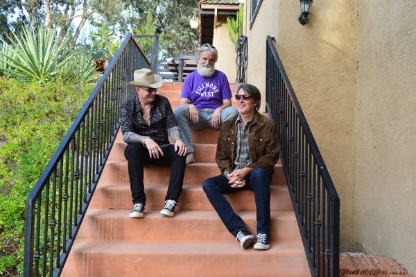 Three men sit on a staircase outside a building in California