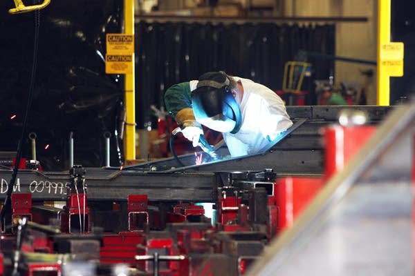 A welder works on a bus at New Flyer