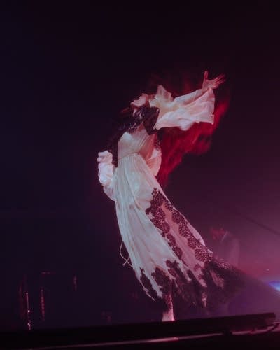 A woman sings into a microphone on a stage