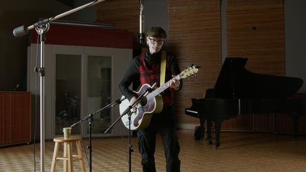 A man plays guitar in a recording studio