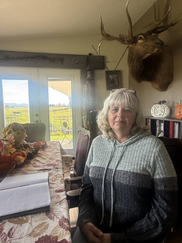 A woman sits for a photo at her dining table.