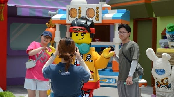 Legoland Shanghai visitors take photos with Lego mascots. The Shanghai government hopes the theme park will encourage spending.