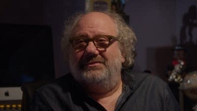 A man wearing glasses speaks to camera