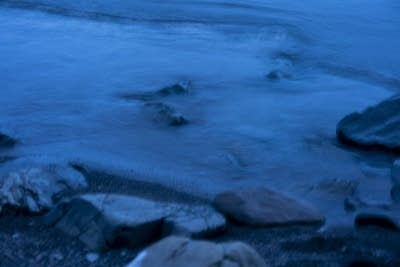 Waves crash on rocks just after sunset.
