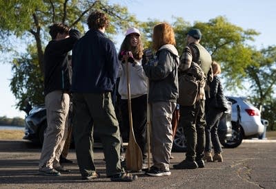 A group of students stand while holding paddles.