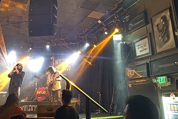 John Nagle, a Jim Morrison impersonator, looks towards a drawing of the actual Jim Morrison while performing on a stage where the late musician used to play.