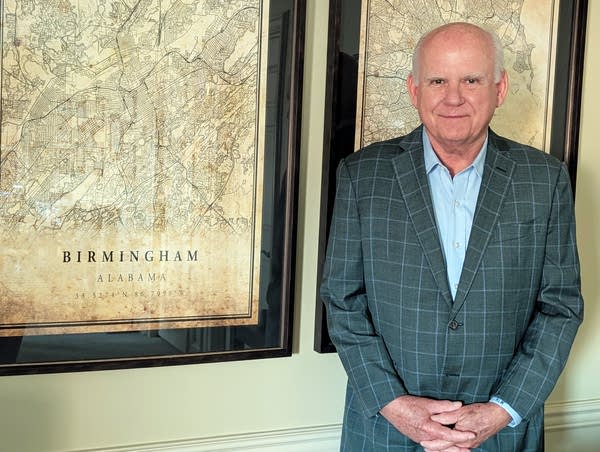 An older man stands in front of a Birmingham map