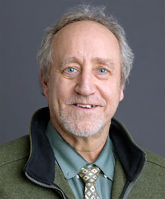 A man in a green jacket poses for a portrait.