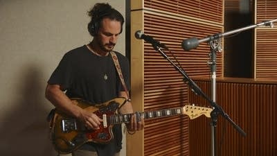 A musician plays slide guitar in a recording studio