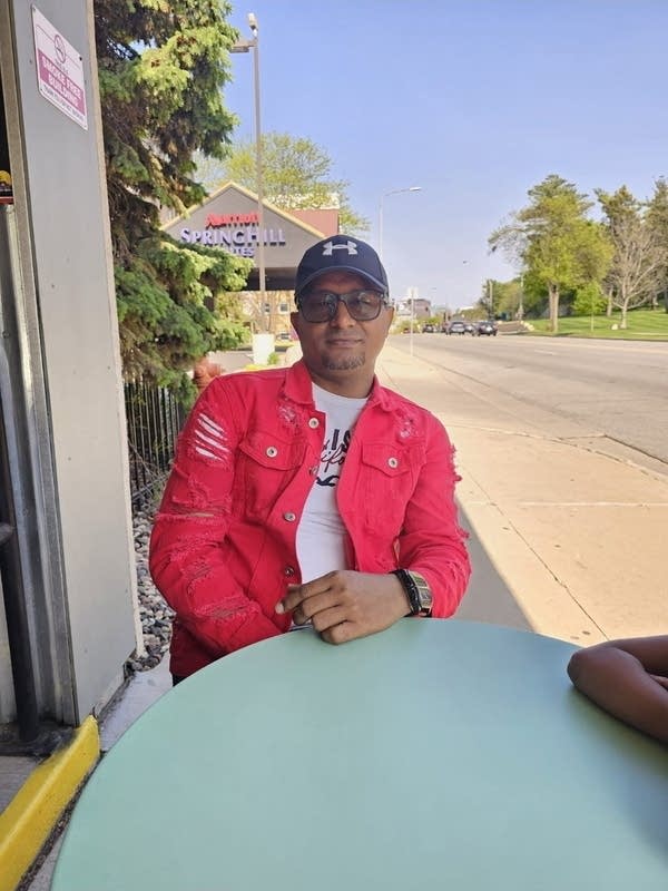 A man sits at a table outside.