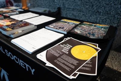 flyers, papers and books stacked across a table