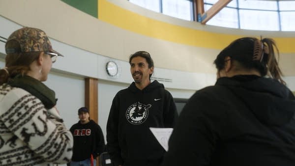 A man talks to a few people inside a building.