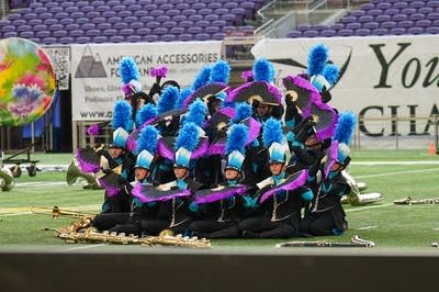 A marching band performs on the field of a football stadium.