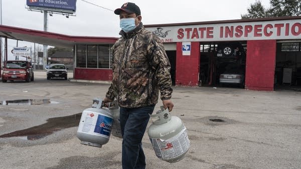 Propane is at the highest prices its been in a decade, a fuel many rural residents rely on for heat. Above, a person carries empty propane tanks to refill in Houston, Texas in February 2021.