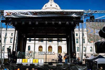 Two musicians perform together on an outdoor stage at a large rally
