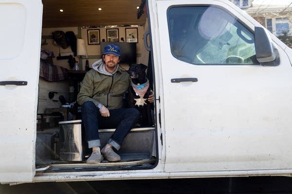 A man poses with his dog in a van