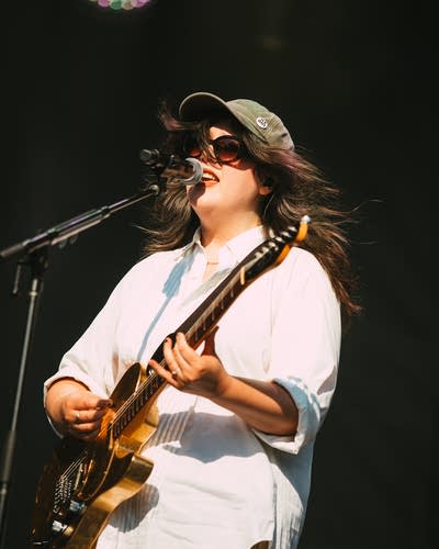 Lucy Dacus performing on stage with a guitar