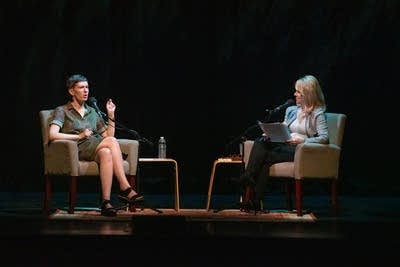 Author Patricia Lockwood and host Kerri Miller converse while sitting in beige armchairs on a large, dark stage.