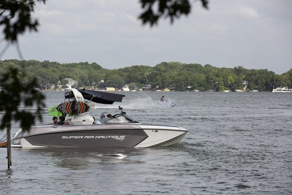 A silver and white wakeboat on the water. 