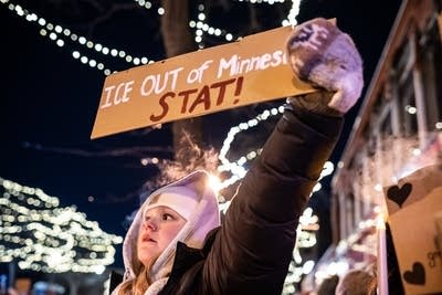 A person holds a sign that says ICE OUT