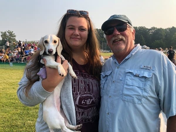 Two people pose for a photo with a dog