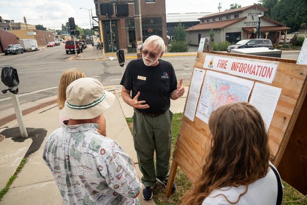 A man speaks to others at an information board.