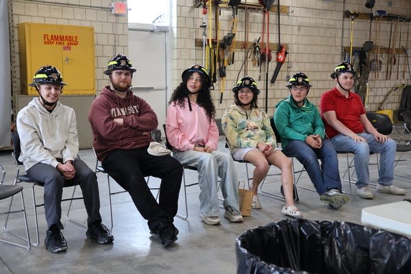 Inclusive Fire Brigade members sitting wearing firefighting helmets